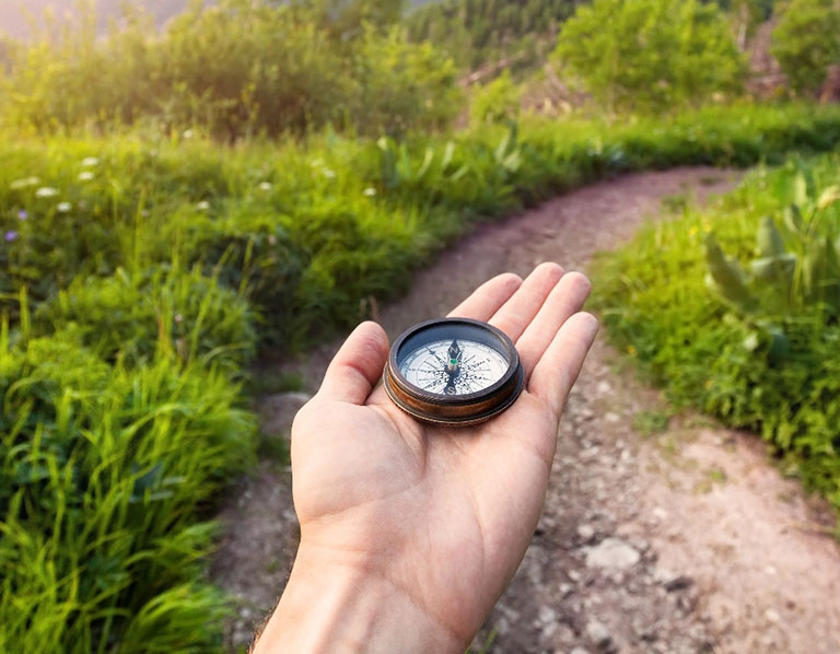 Hand holding compass walking along path