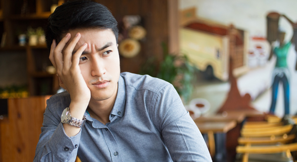 Bored young Asian man sitting in cafe
